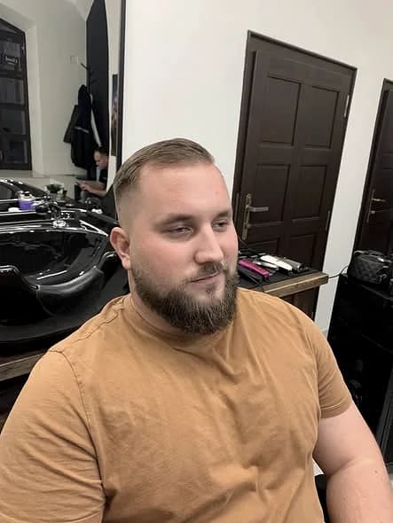Hotový střih s upravenými vousy, klient v křesle holičství