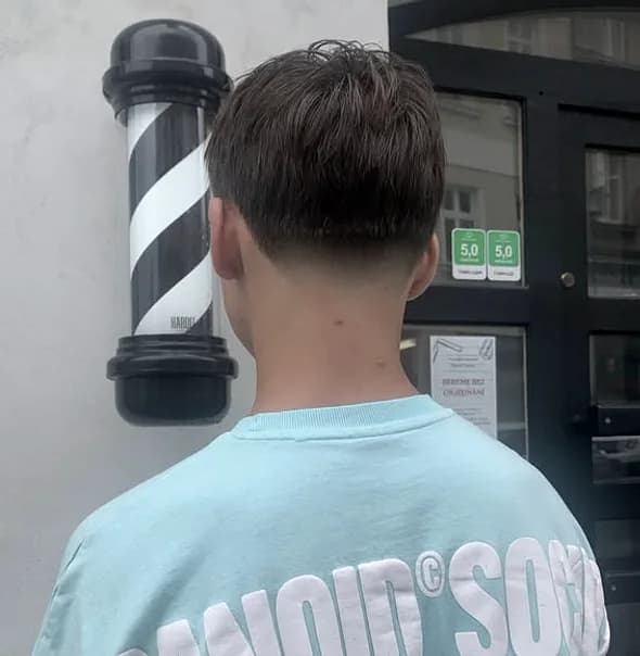 Čistý přechod střihu zezadu, v pozadí barber pole u vchodu