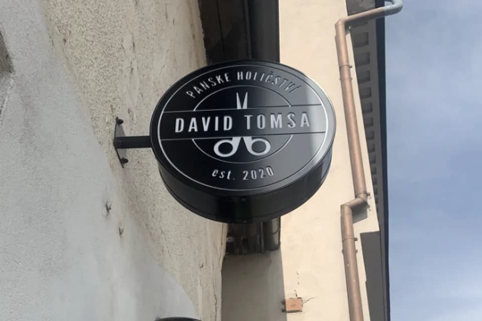 Kruhová cedule Pánského holičství David Tomsa a barber pole na fasádě v Turnově
