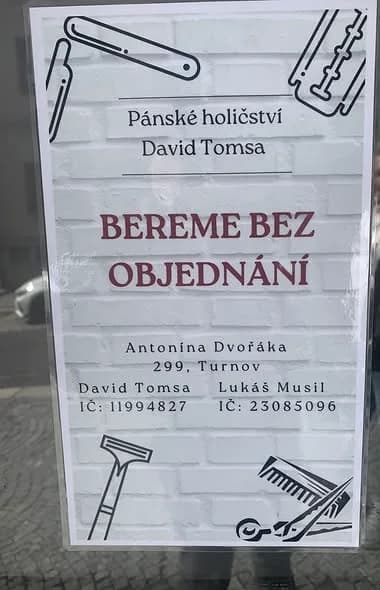 Cedule ve výloze holičství s nápisem Bereme bez objednání